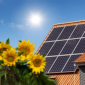 haus-mit-photovoltaik-zellen-auf-dach-und-sonnenblumen-sommer Photovoltaik-Anlage im Sommer